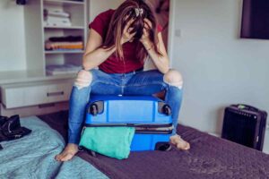 mujer sobre maleta que no se cierra